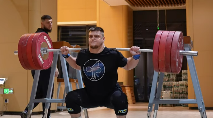 A man performing a back squat.